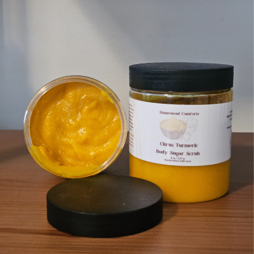 A creamy, exfoliating sugar scrub infused with turmeric and uplifting citrus essential oils to smooth, brighten, and nourish skin while invigorating the senses, tipped over to view the inside. 