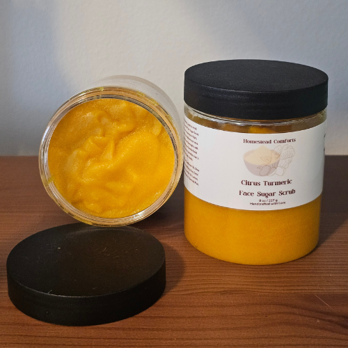 A nourishing sugar scrub with turmeric and citrus essential oils that gently exfoliates, smooths skin texture, and promotes a radiant, even-toned complexion, on it side to view the texture of the sugar scrub. 